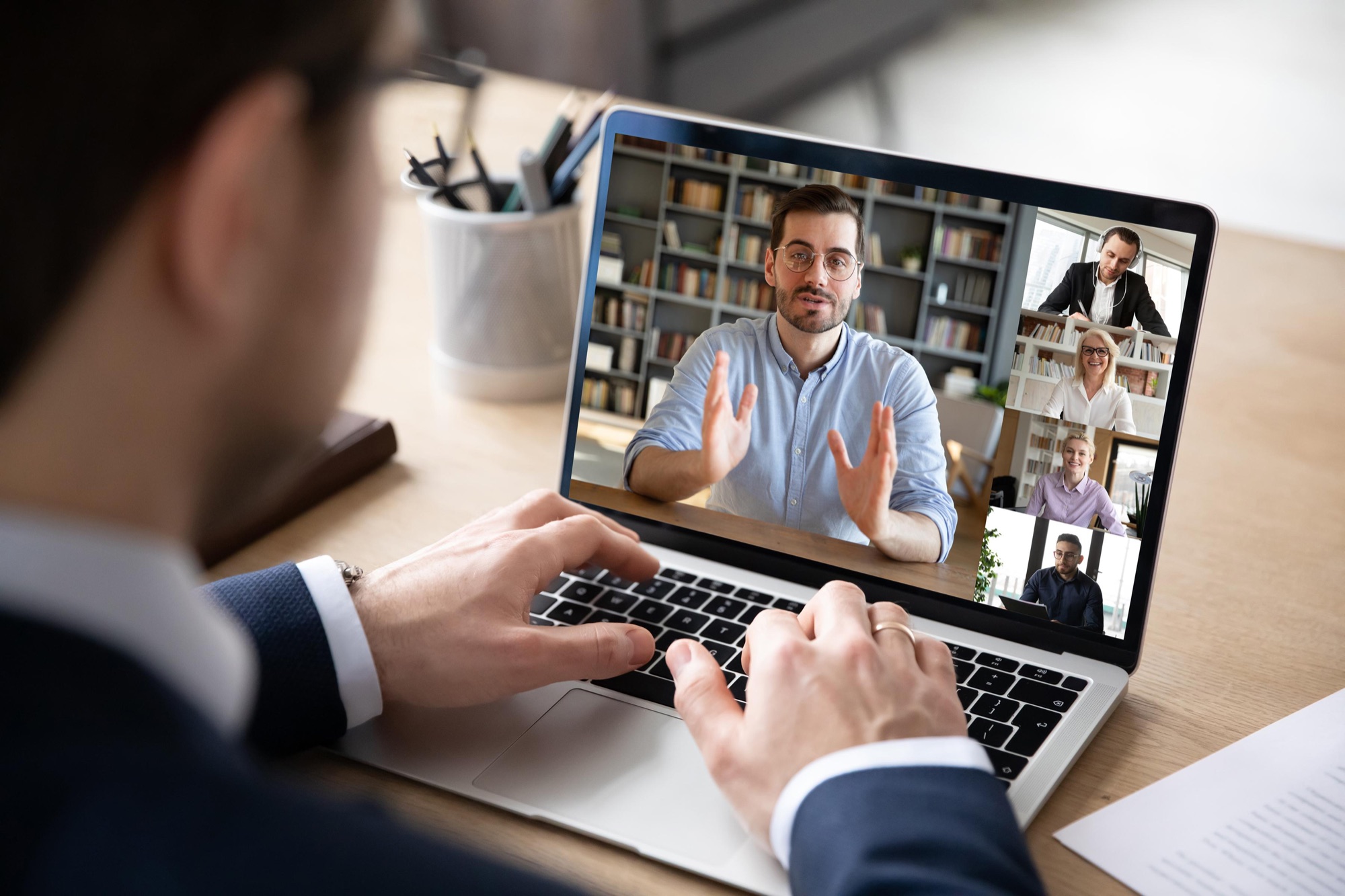 Looking over a laptop during a video call with a team of five people